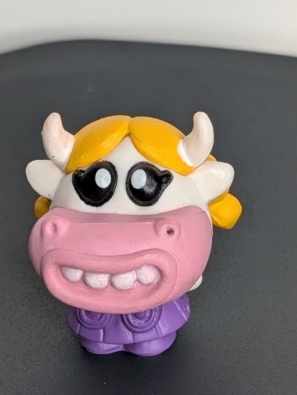 Cute cow figurine with yellow hair and purple dress